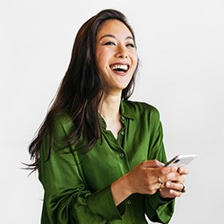 woman smiling and laughing while holding her phone