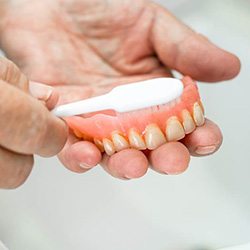 hands brushing dentures