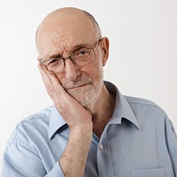 older man holding his face