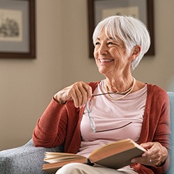 older woman smiling and reading a book