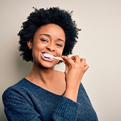 Woman in blue sweater brushing her teeth