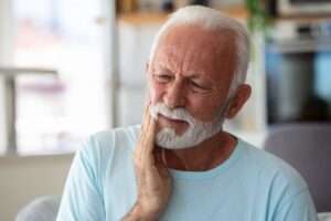 older man holding his face in discomfort